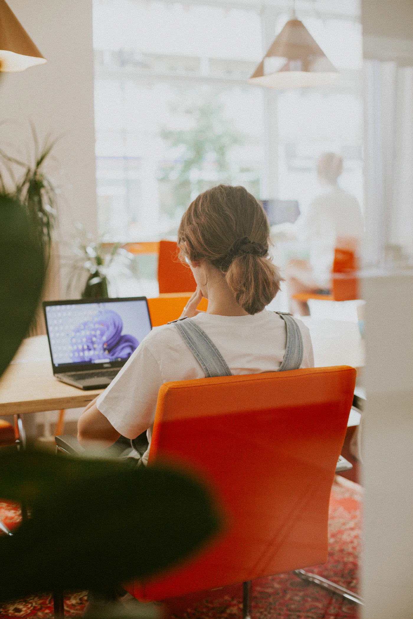 Osoba pracująca na laptopie przy wspólnym stole w coworkingu ko_stacja w Koszalinie.