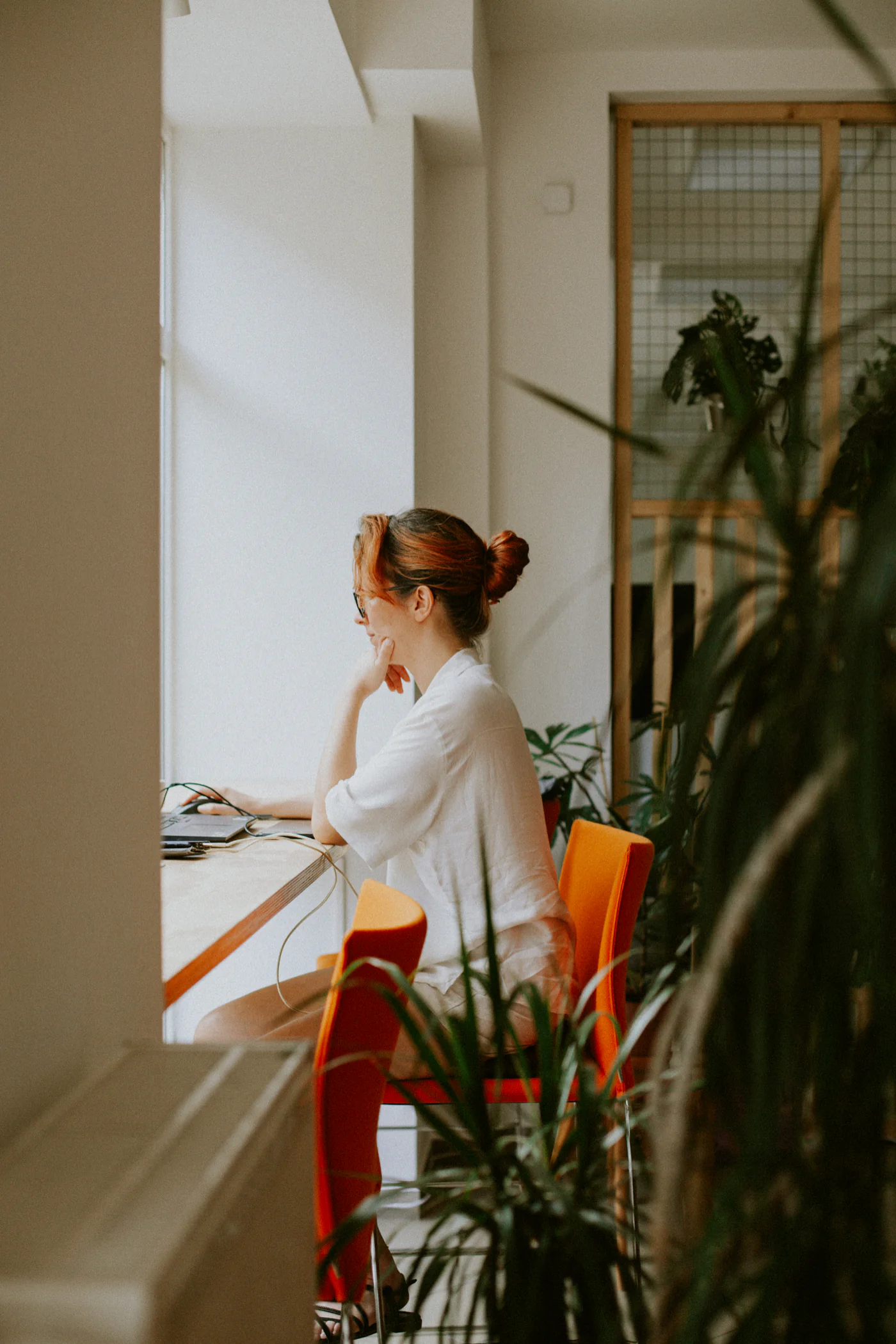 Stanowisko pracy przy blacie w witrynie coworkingu, przy świetle dziennym i twarzą do miasta.