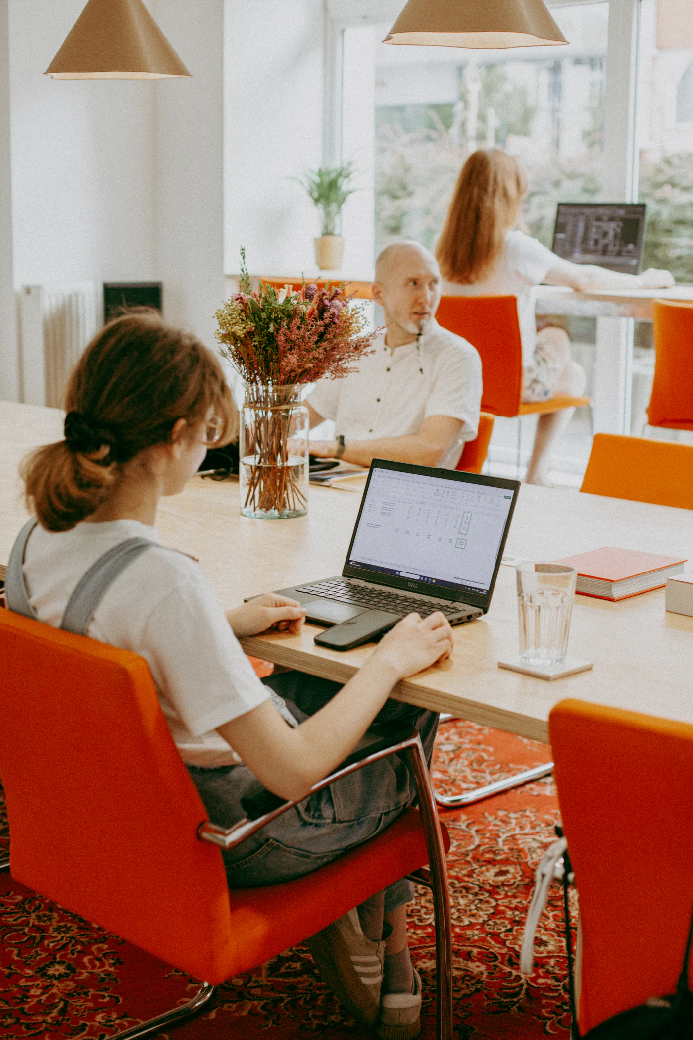 Goście coworkingu ko_stacja pracujący na laptopach przy dużym wspólnym stole na osiem miejsc.